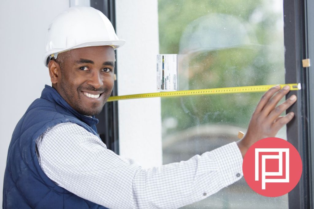 An access consultant wearing a hardhat is measuring a door clearance